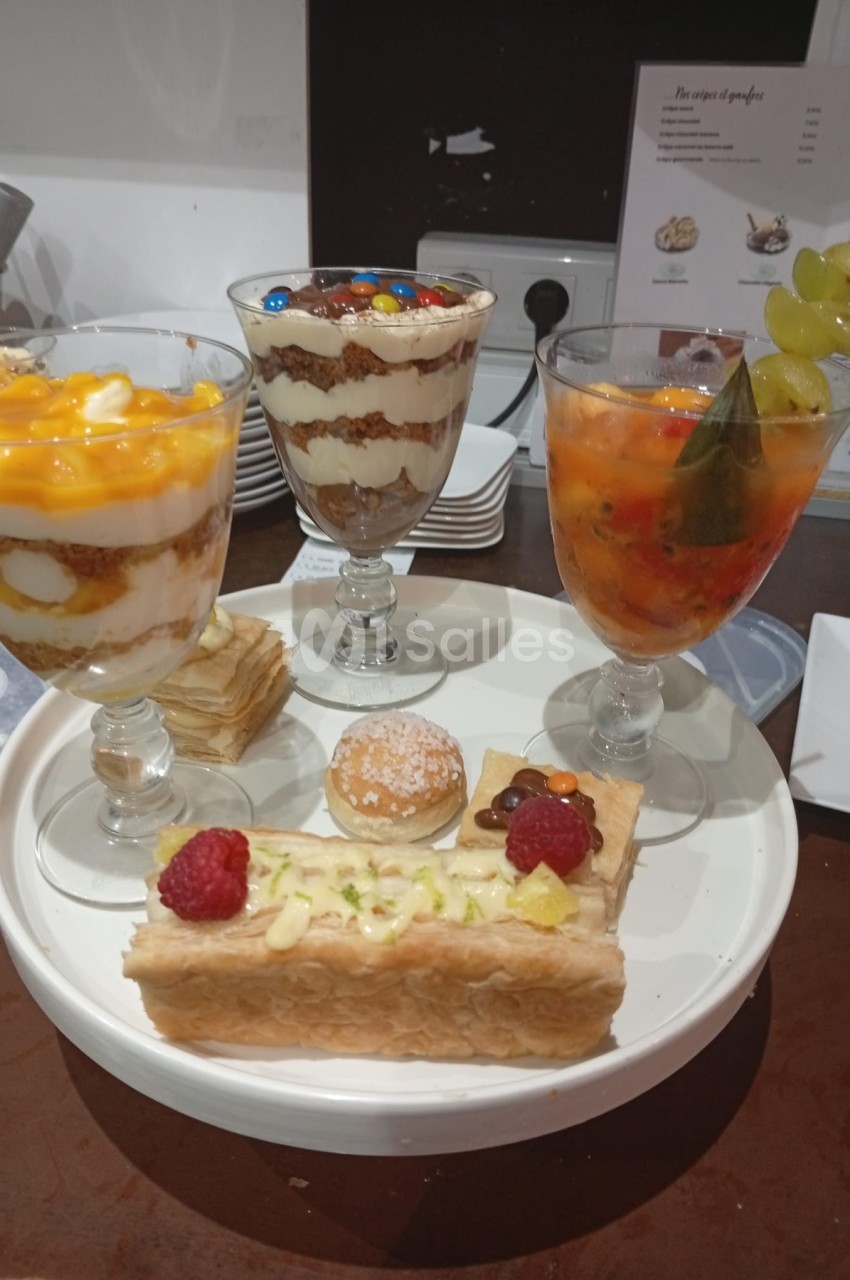 Assiette de pâtisseries et verrines en verre avec couches de crème et fruits, accompagnées de trois desserts en verre.