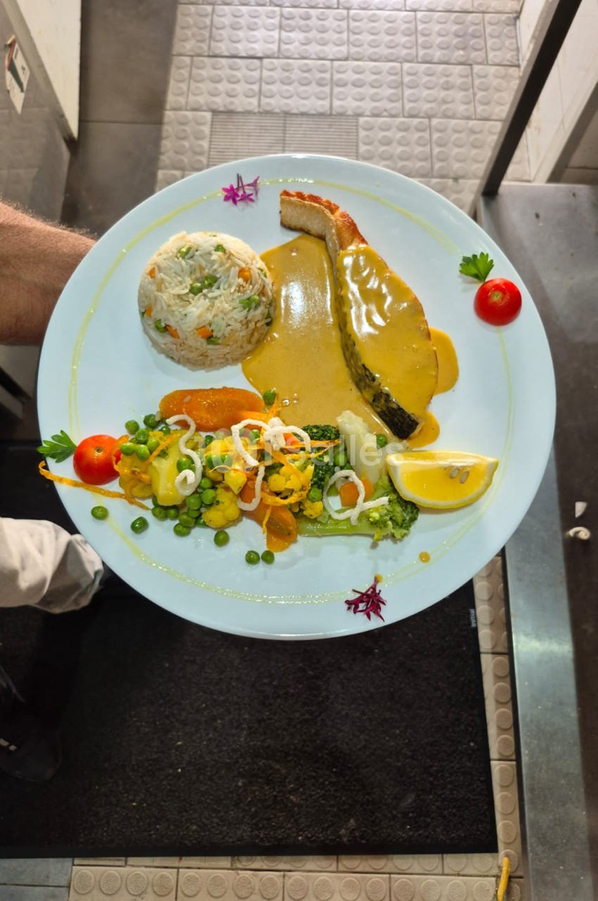 Assiette de poisson entier en sauce jaune avec riz, légumes et citron - cuisine gastronomique.