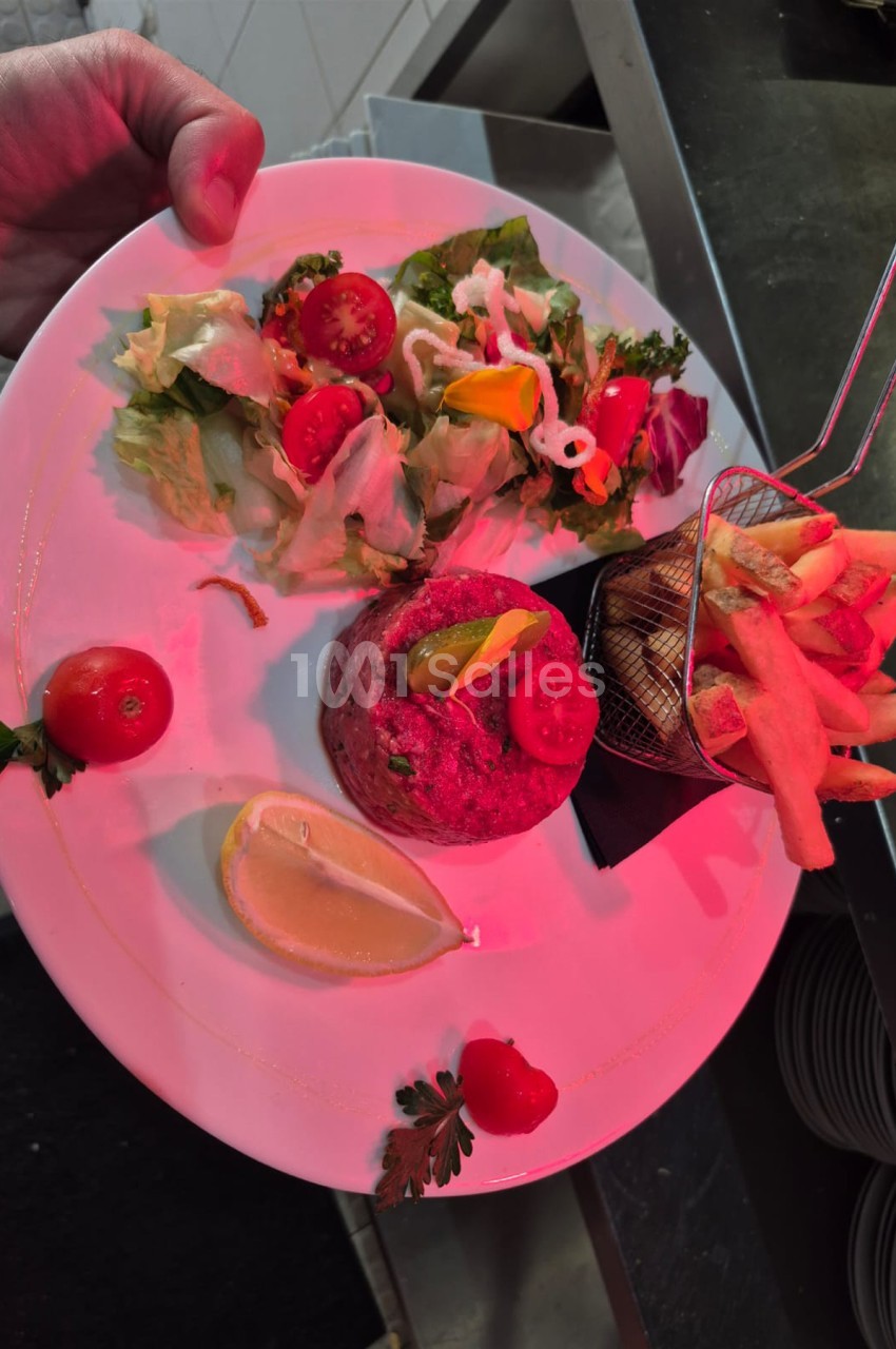 Assiette rose avec composition culinaire - tomate, betterave, fleurs comestibles et feuilles vertes.