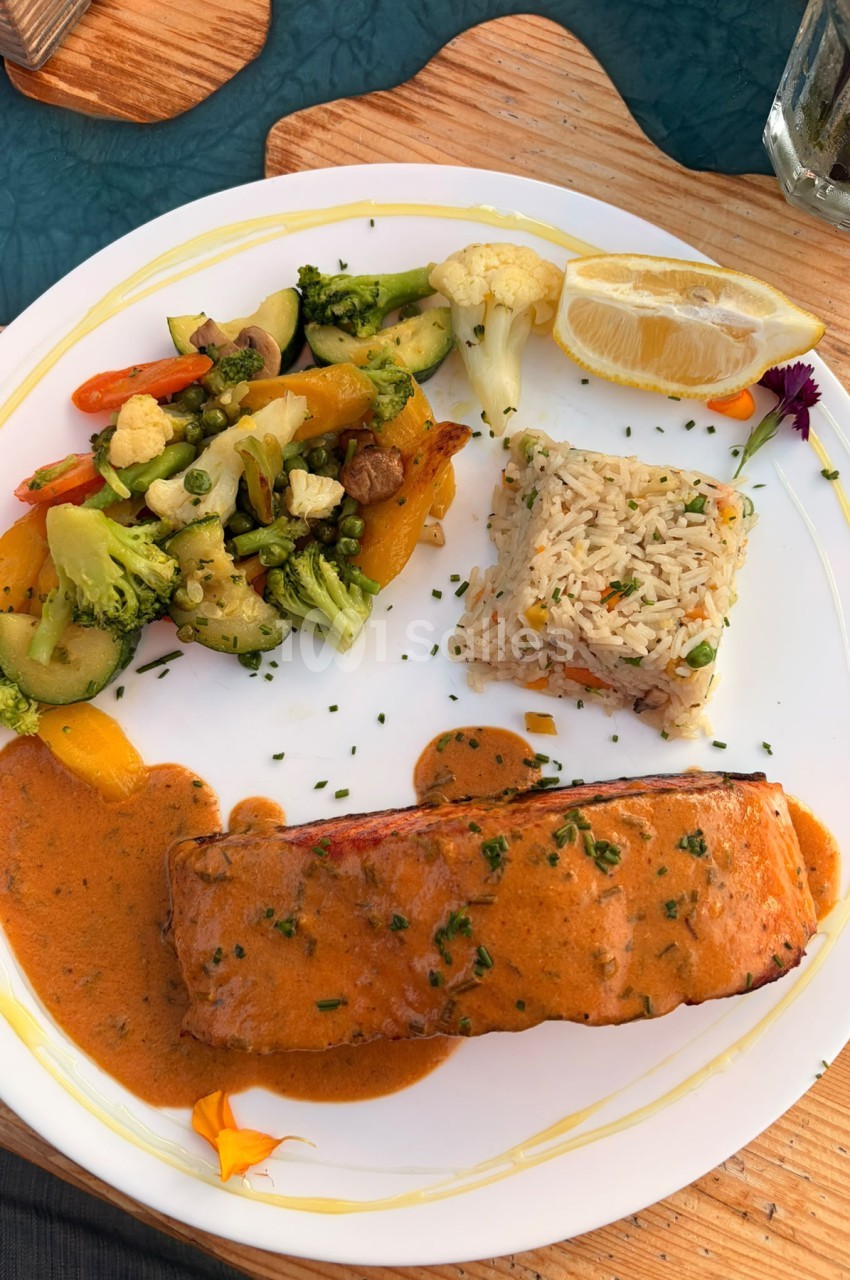 Assiette dressée avec filet de poisson sauce orange, légumes variés et riz aux herbes.