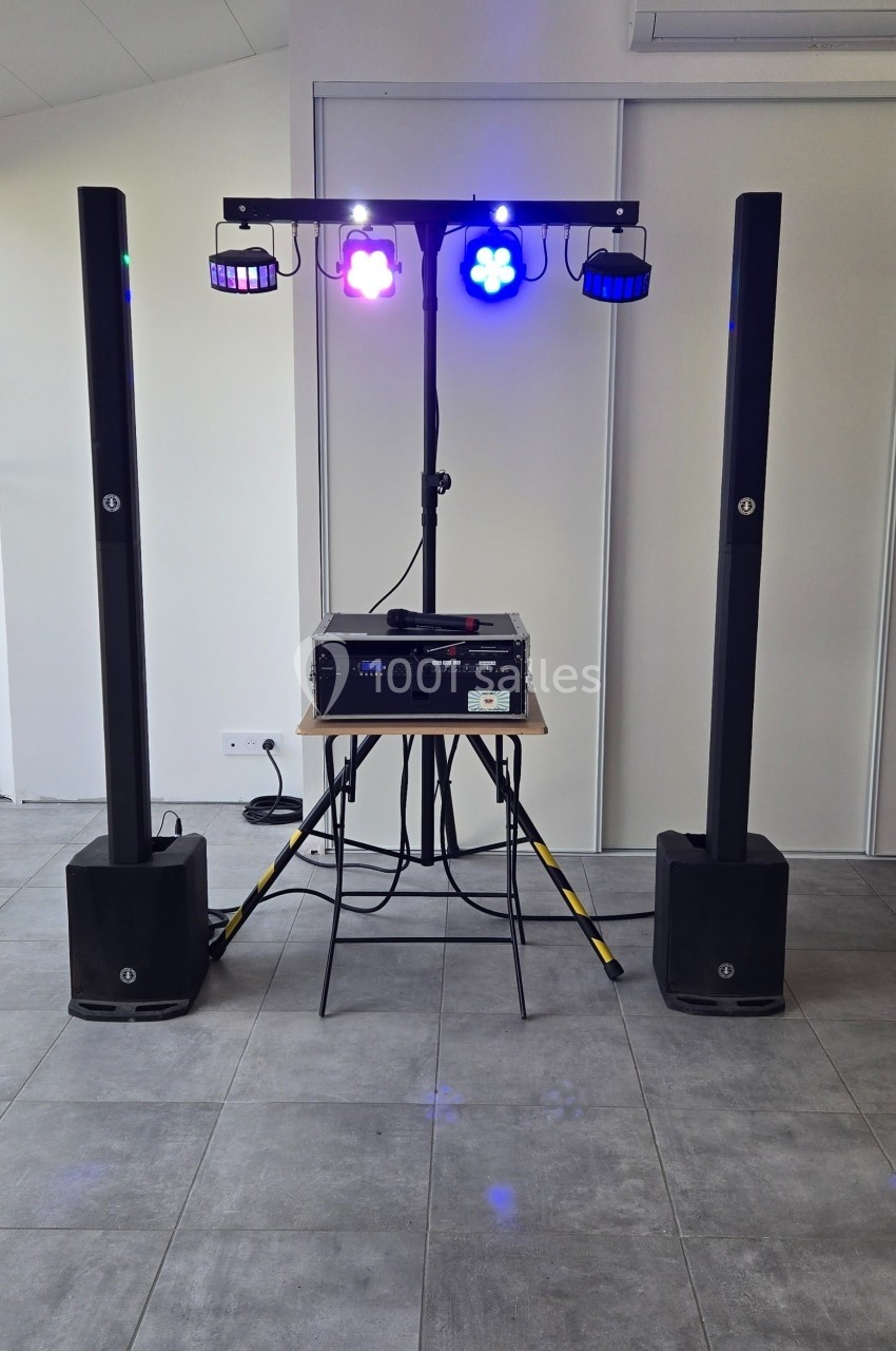 Équipement de sonorisation et éclairage avec deux enceintes, une table de mixage et des projecteurs colorés.