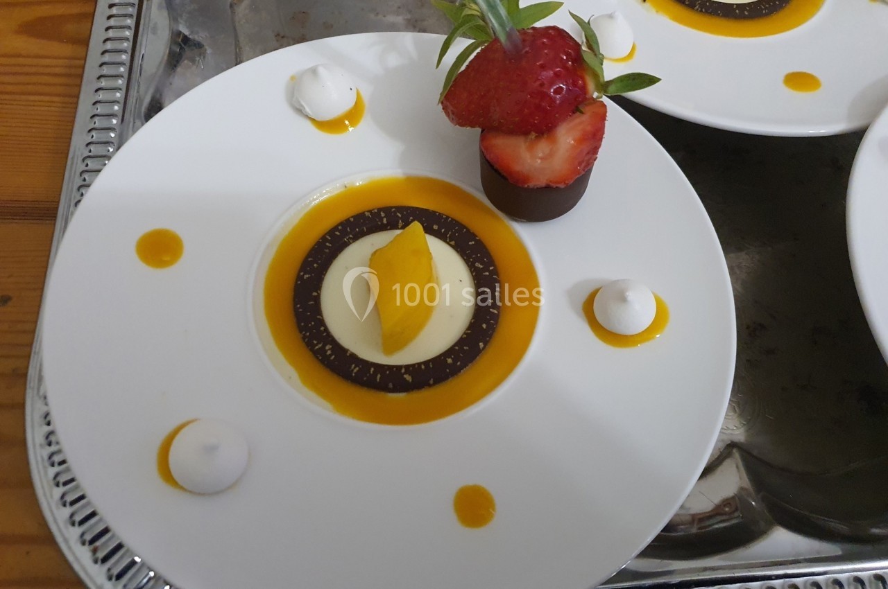 Assiette de dessert composée d'une mousse, d'un coulis orange, d'une fraise et de petites touches de meringue.