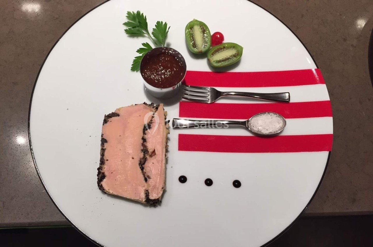 Assiette gastronomique avec terrine, sauce, sel, kiwi, tomate cerise et décorations géométriques rouges.