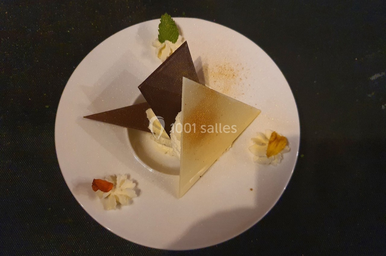 Assiette de dessert avec des triangles de chocolat noir et blanc, crème fouettée et décorations.