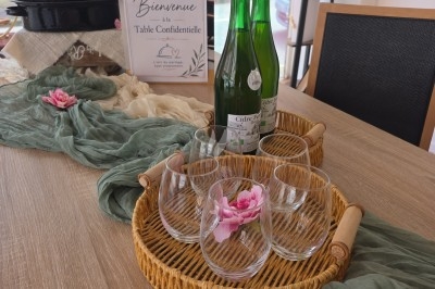 Miniature Traiteur Gacé (Orne) - La Table Confidentielle #28 Affiche décorative avec des herbes aromatiques, deux flacons en verre et une branche de romarin sur une table en bois.