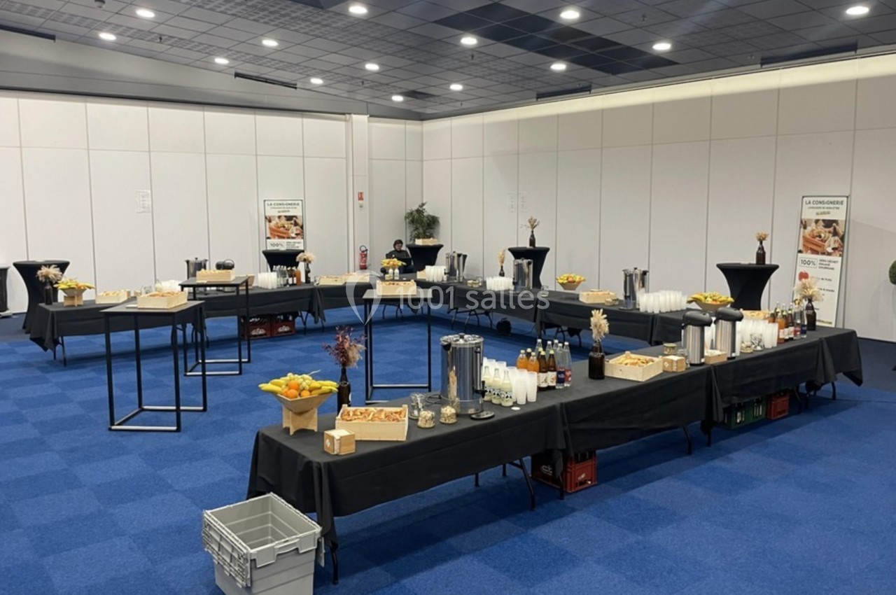 Buffet de petit-déjeuner avec boissons chaudes, jus, viennoiseries et fruits, disposé sur des tables dans une salle.