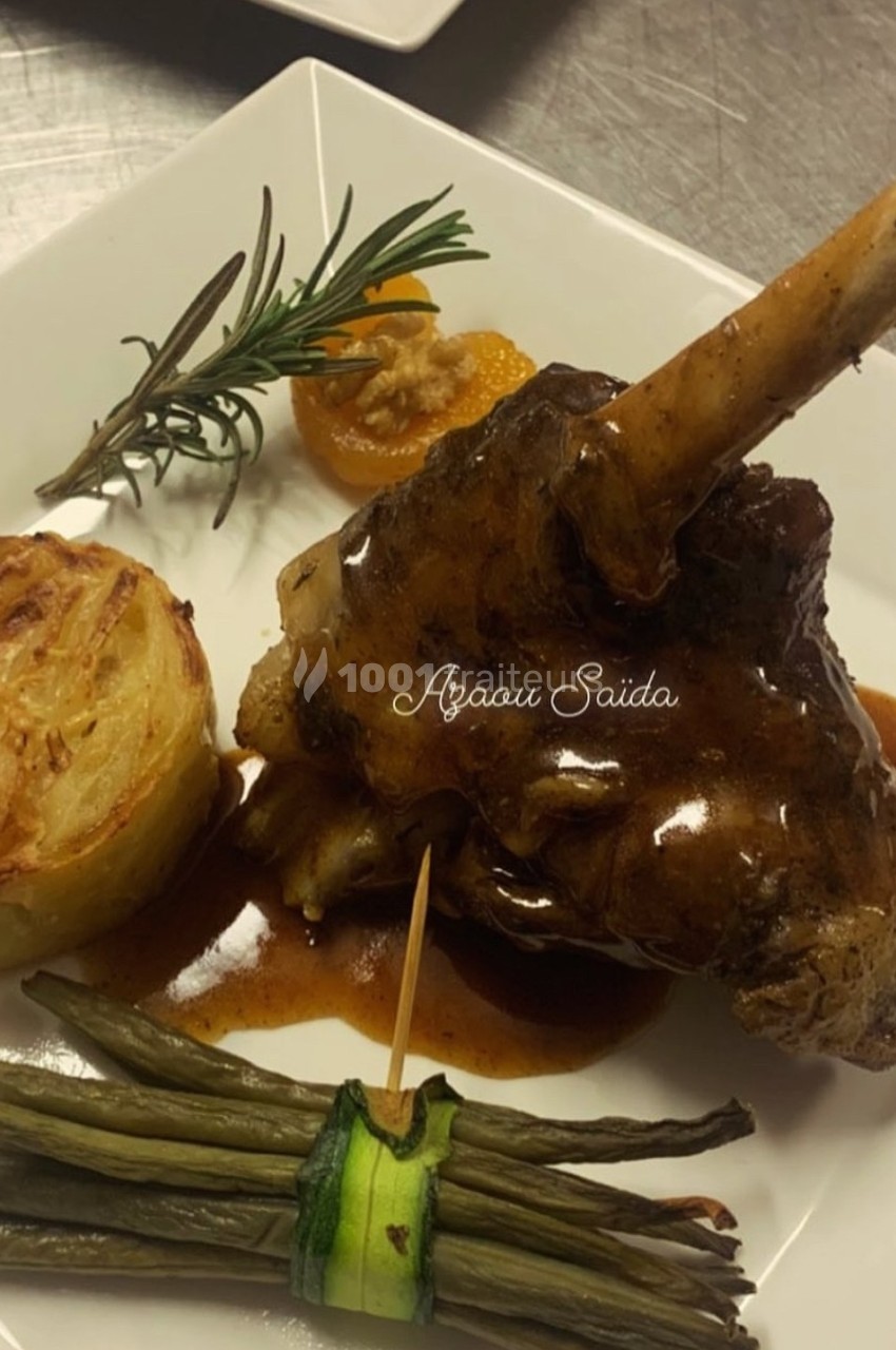 Plat de jarret d'agneau en sauce, accompagné de gratin dauphinois, haricots verts et décoration d'herbes.