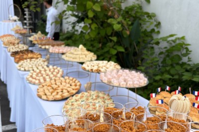 Buffet en extérieur avec une variété de desserts et amuse-bouches disposés sur des tables alignées.