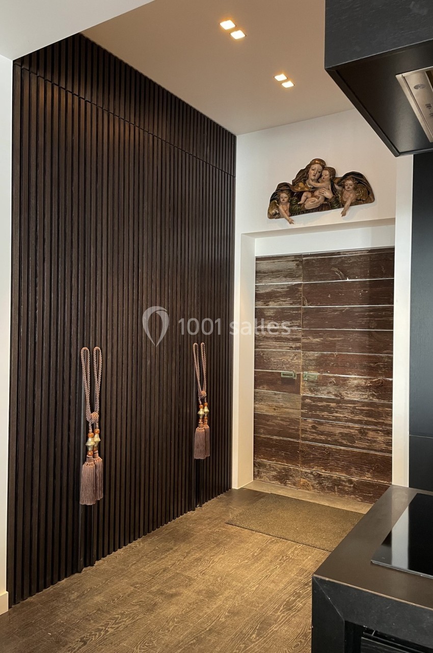 Mur en bois sombre avec des cordons décoratifs, porte en marbre brun et sculpture murale au-dessus dans un intérieur moderne.