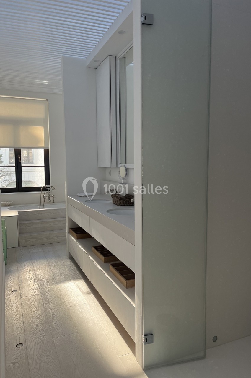 Salle de bain moderne avec lavabo, étagères ouvertes, grande fenêtre et lumière naturelle.