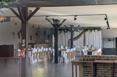 Miniature Location salle Saint-Guyomard (Morbihan) - Domaine de Ker Léon #19 Espace extérieur avec tables hautes noires sur une pelouse, devant un bâtiment vitré et un comptoir en bois.