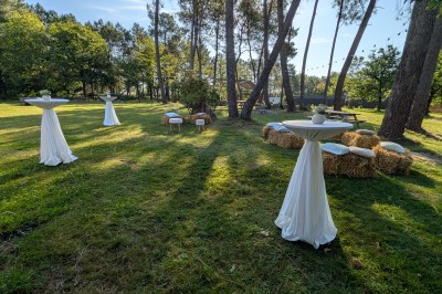 Miniature Location salle Saint-Guyomard (Morbihan) - Domaine de Ker Léon #3 Espace extérieur avec tables hautes noires sur une pelouse, devant un bâtiment vitré et un comptoir en bois.