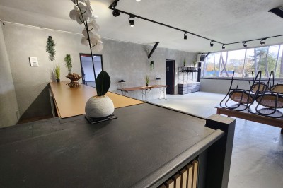 Miniature Location salle Saint-Guyomard (Morbihan) - Domaine de Ker Léon #22 Espace extérieur avec tables hautes noires sur une pelouse, devant un bâtiment vitré et un comptoir en bois.