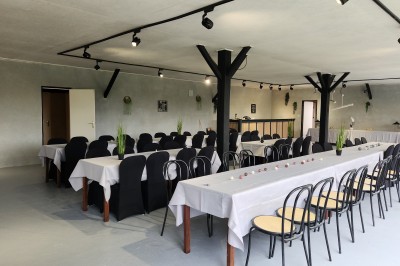Miniature Location salle Saint-Guyomard (Morbihan) - Domaine de Ker Léon #15 Espace extérieur avec tables hautes noires sur une pelouse, devant un bâtiment vitré et un comptoir en bois.