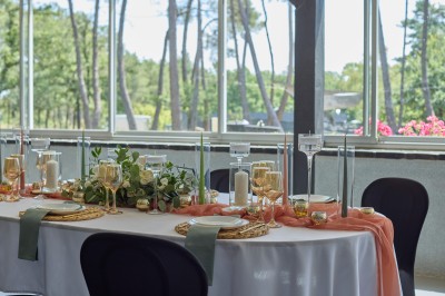 Miniature Location salle Saint-Guyomard (Morbihan) - Domaine de Ker Léon #21 Espace extérieur avec tables hautes noires sur une pelouse, devant un bâtiment vitré et un comptoir en bois.
