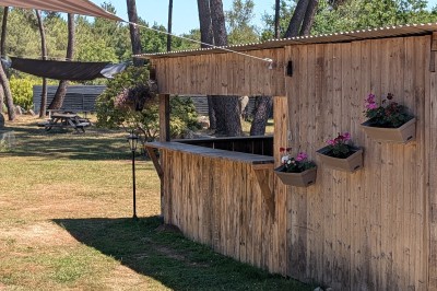 Miniature Location salle Saint-Guyomard (Morbihan) - Domaine de Ker Léon #42 Espace extérieur avec tables hautes noires sur une pelouse, devant un bâtiment vitré et un comptoir en bois.