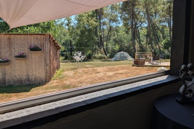 Miniature Location salle Saint-Guyomard (Morbihan) - Domaine de Ker Léon #43 Espace extérieur avec tables hautes noires sur une pelouse, devant un bâtiment vitré et un comptoir en bois.