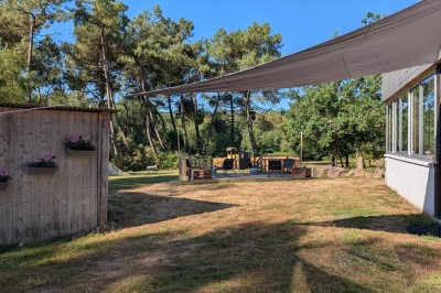 Miniature Location salle Saint-Guyomard (Morbihan) - Domaine de Ker Léon #59 Espace extérieur avec tables hautes noires sur une pelouse, devant un bâtiment vitré et un comptoir en bois.