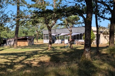 Miniature Location salle Saint-Guyomard (Morbihan) - Domaine de Ker Léon #60 Espace extérieur avec tables hautes noires sur une pelouse, devant un bâtiment vitré et un comptoir en bois.