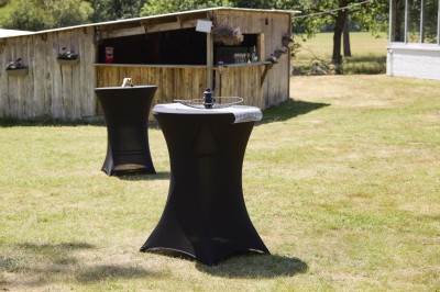 Miniature Location salle Saint-Guyomard (Morbihan) - Domaine de Ker Léon #71 Espace extérieur avec tables hautes noires sur une pelouse, devant un bâtiment vitré et un comptoir en bois.