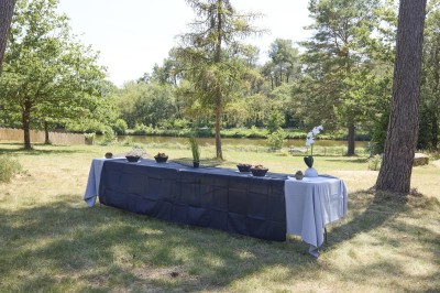 Miniature Location salle Saint-Guyomard (Morbihan) - Domaine de Ker Léon #91 Espace extérieur avec tables hautes noires sur une pelouse, devant un bâtiment vitré et un comptoir en bois.