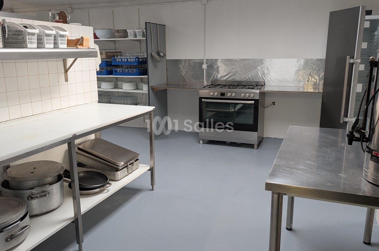 Cuisine professionnelle avec plan de travail inox, four, cuisinière gaz, rangements et équipements de restauration collective.