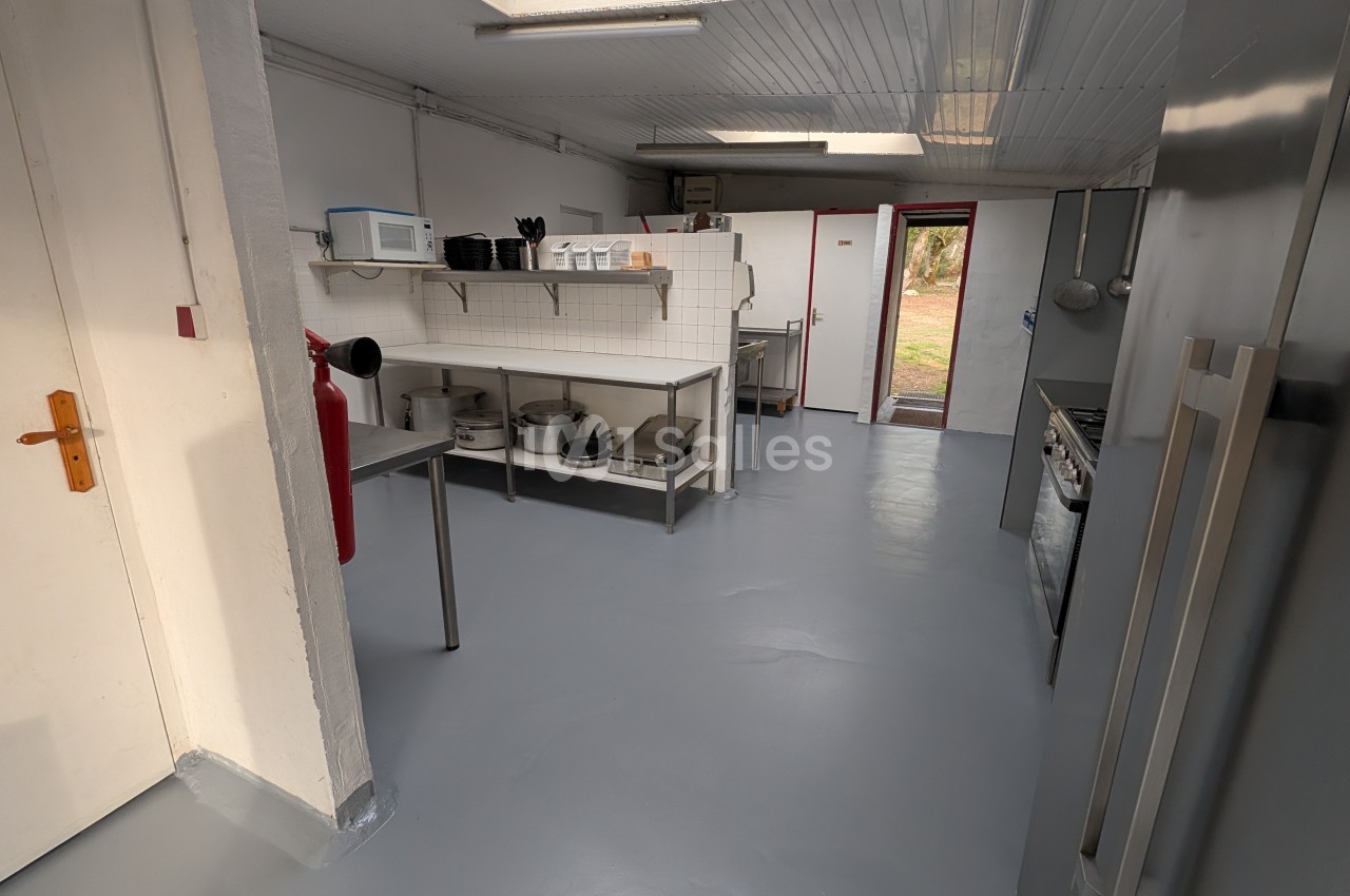 Cuisine professionnelle avec plans de travail, étagères murales, réfrigérateur et four - espace blanc et gris au sol époxy.