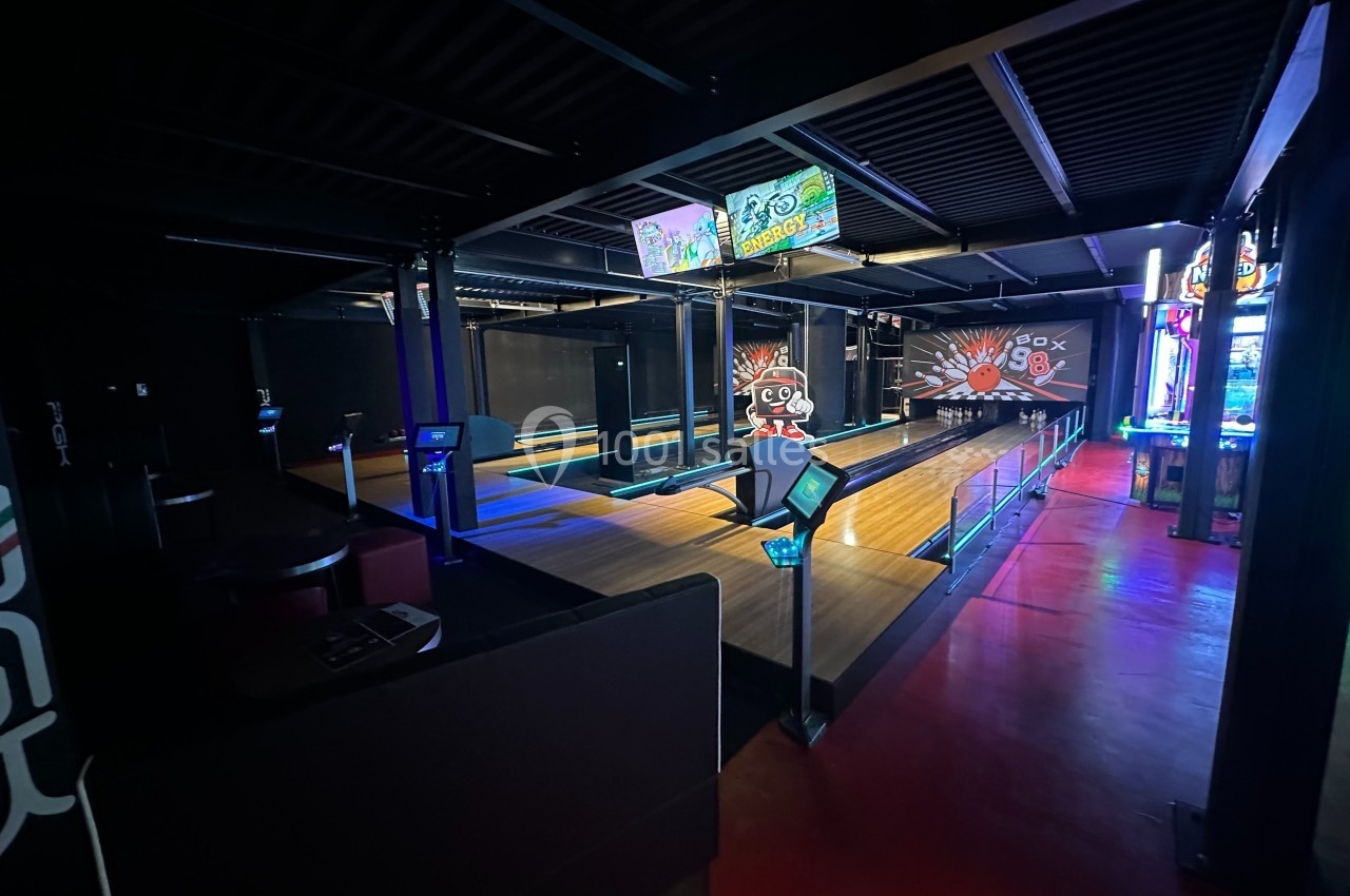 Piste de bowling moderne avec éclairage tamisé, écrans d'affichage et ambiance de salle de loisirs.