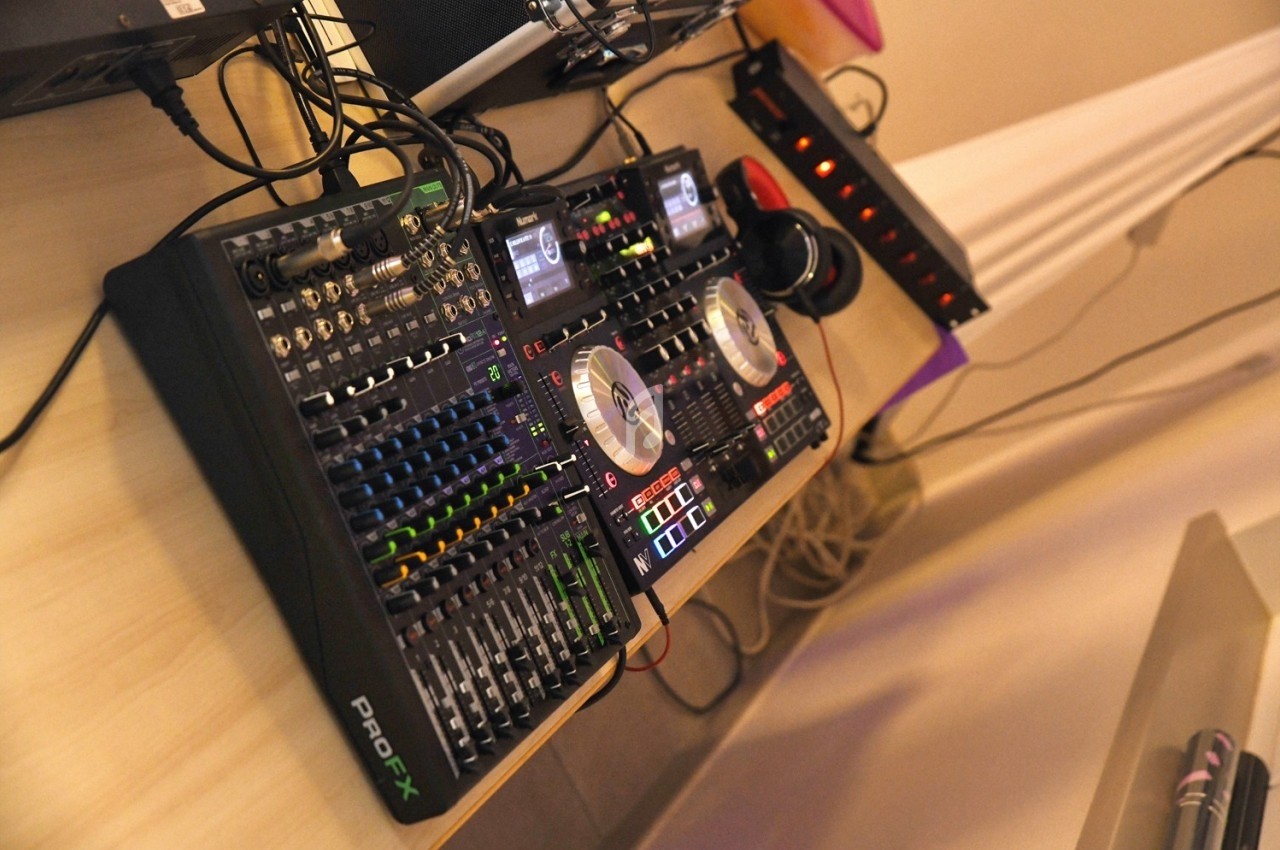 Table de mixage audio avec platines, curseurs, boutons et casque, installée sur un bureau dans un environnement intérieur.