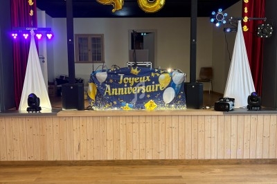 Décoration de scène pour un 40e anniversaire avec ballons dorés, guirlandes et équipement de sonorisation.