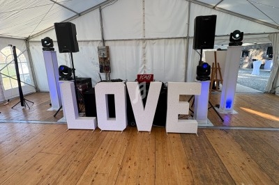 Lettres géantes formant le mot ’LOVE’ dans une tente décorée avec des lumières et un espace pour DJ.