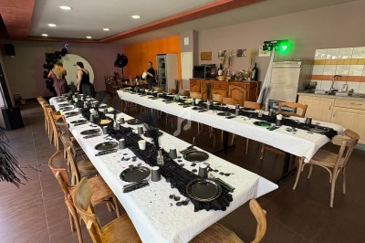 Salle décorée avec deux longues tables dressées avec vaisselle noire et blanche, prête pour un événement festif.