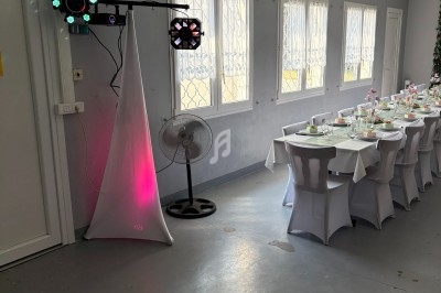 Salle décorée pour un événement, avec une table dressée et un éclairage d'ambiance près d'un ventilateur.