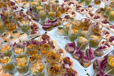 Plateaux de verrines et amuse-bouches variés disposés pour un buffet ou un événement.