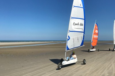 Un groupe de personnes s'étire sur une plage de sable près de la mer sous un ciel nuageux.