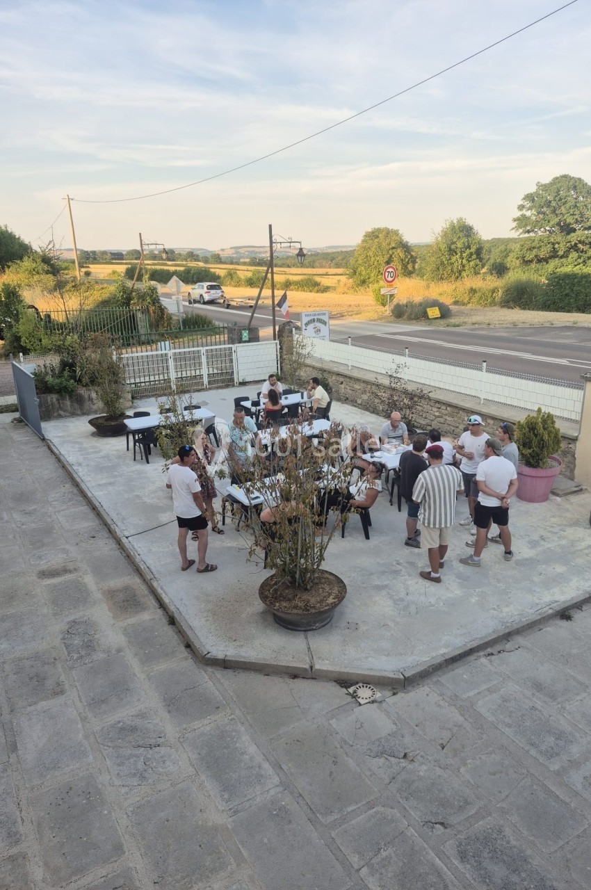 Groupe de personnes discutant et partageant un moment convivial sur une terrasse extérieure par temps ensoleillé.