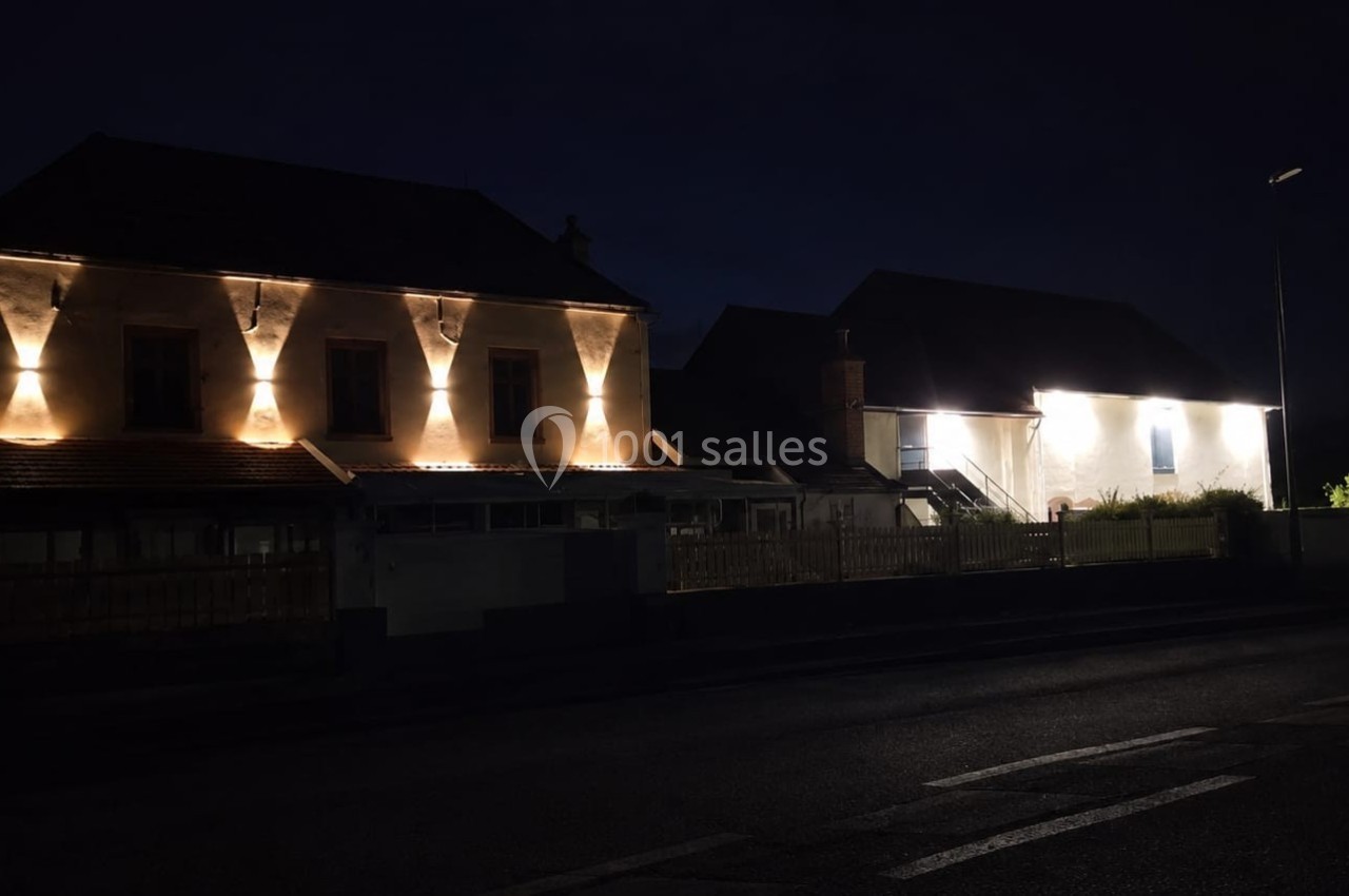 Façades de maisons éclairées par des lumières chaudes dans une rue sombre pendant la nuit.