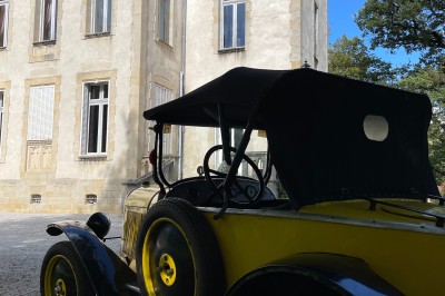 Miniature Location salle Castres (Tarn) - Château du Causse #20 Voiture ancienne jaune et noire stationnée devant un bâtiment historique en pierre, sous un ciel partiellement dégagé.