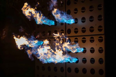 Miniature Rêves de Feu #8 Colonnes de panneaux métalliques perforés émettant des flammes dans un environnement extérieur nocturne.