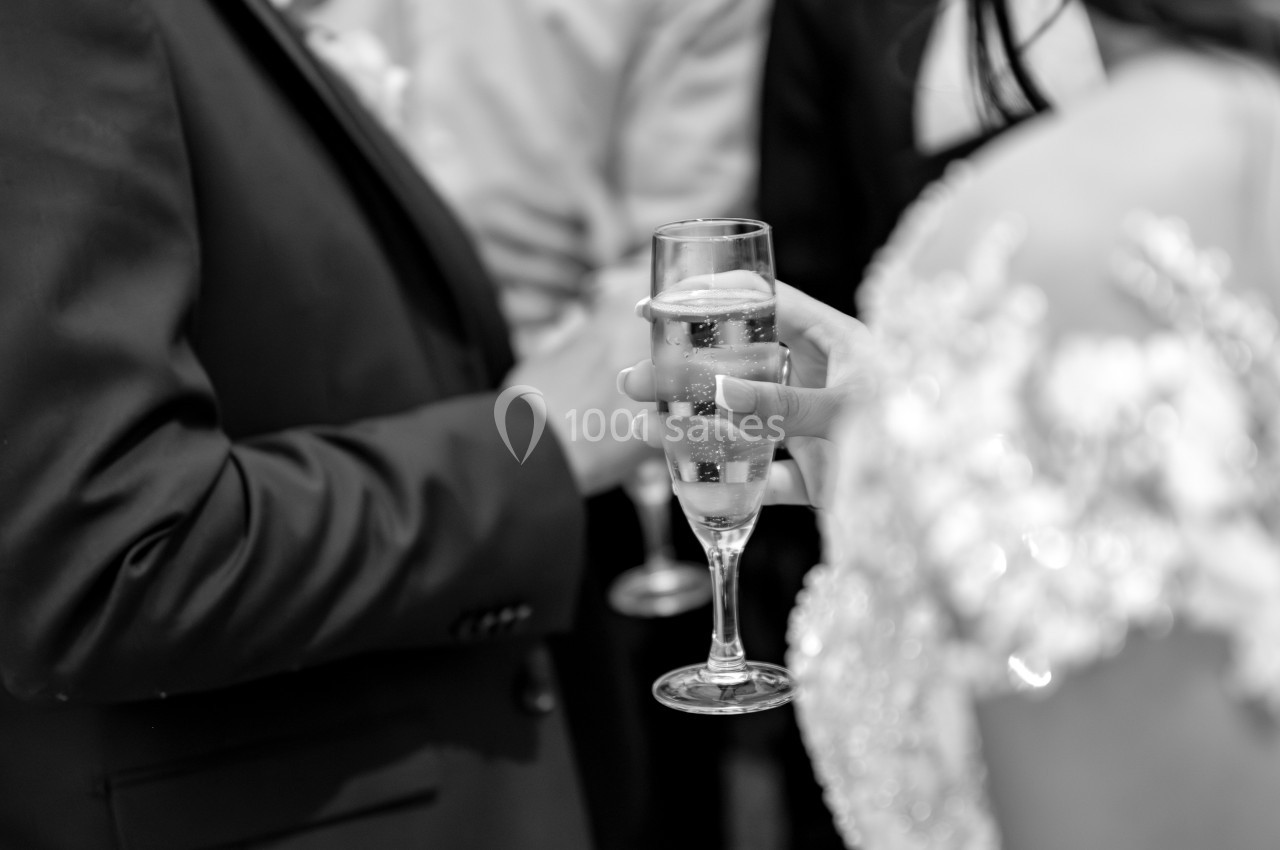 Une personne en tenue élégante tient une flûte de champagne lors d'un événement formel.