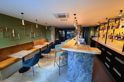 Miniature Salle Bar entrée Salle de restaurant moderne avec murs verts, banquette jaune, chaises bleues et tables rondes en bois clair.