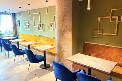 Miniature Salle Bar Salle de restaurant moderne avec murs verts, banquette jaune, chaises bleues et tables rondes en bois clair.