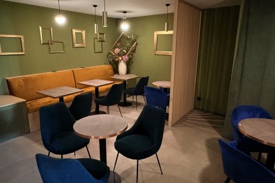 Miniature Location salle Lyon 5 (Rhône) - Les Petits Caprices #3 Salle de restaurant moderne avec murs verts, banquettes orange, chaises bleues et tables en bois clair.