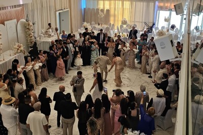 Salle extérieure aménagée avec des tables hautes noires, décorations florales blanches et lumière naturelle.
