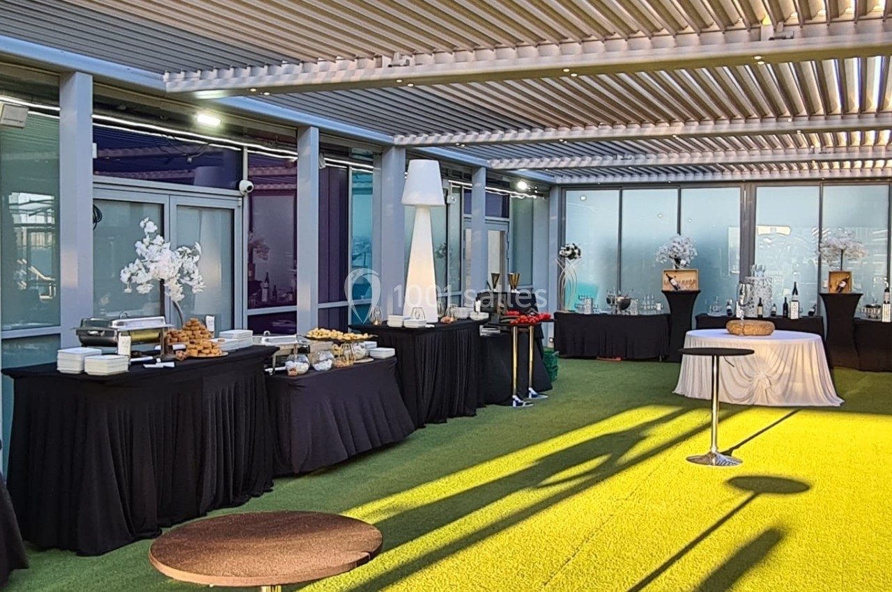 Buffet installé sous une pergola avec nappes noires et blanches, tables garnies de plats et décorations florales.