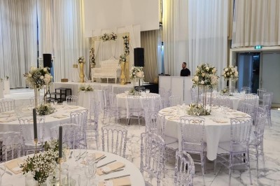 Salle extérieure aménagée avec des tables hautes noires, décorations florales blanches et lumière naturelle.