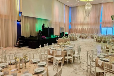 Salle extérieure aménagée avec des tables hautes noires, décorations florales blanches et lumière naturelle.