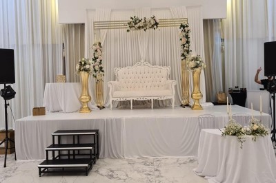 Salle extérieure aménagée avec des tables hautes noires, décorations florales blanches et lumière naturelle.