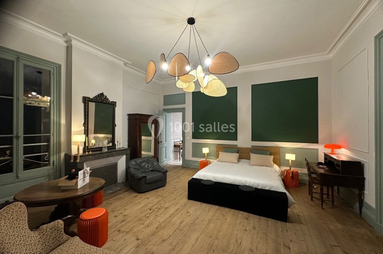 Chambre spacieuse avec lit double, mobilier élégant, parquet, éclairage design et murs décorés de panneaux verts.