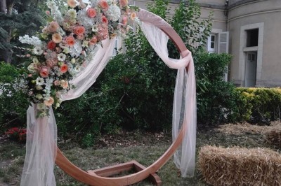Miniature cérémonie laïque Un couple en tenue de mariage marche dans une salle en briques, avec un bouquet de fleurs au premier plan.